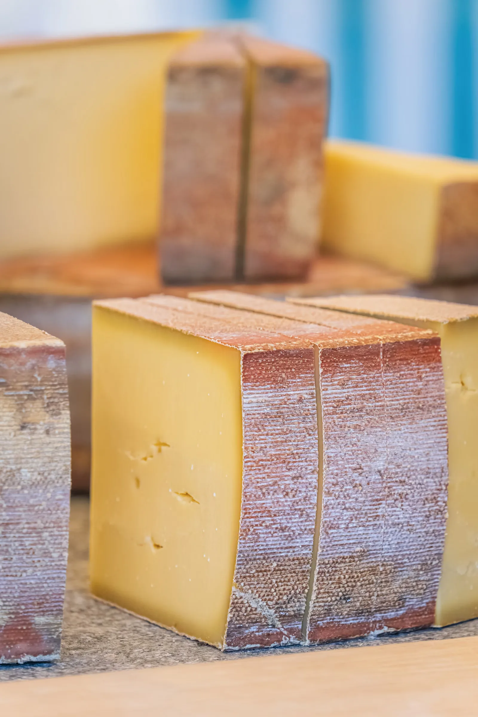 Tranches de fromage artisanal présentant leur texture et leur croûte sur une surface en bois.